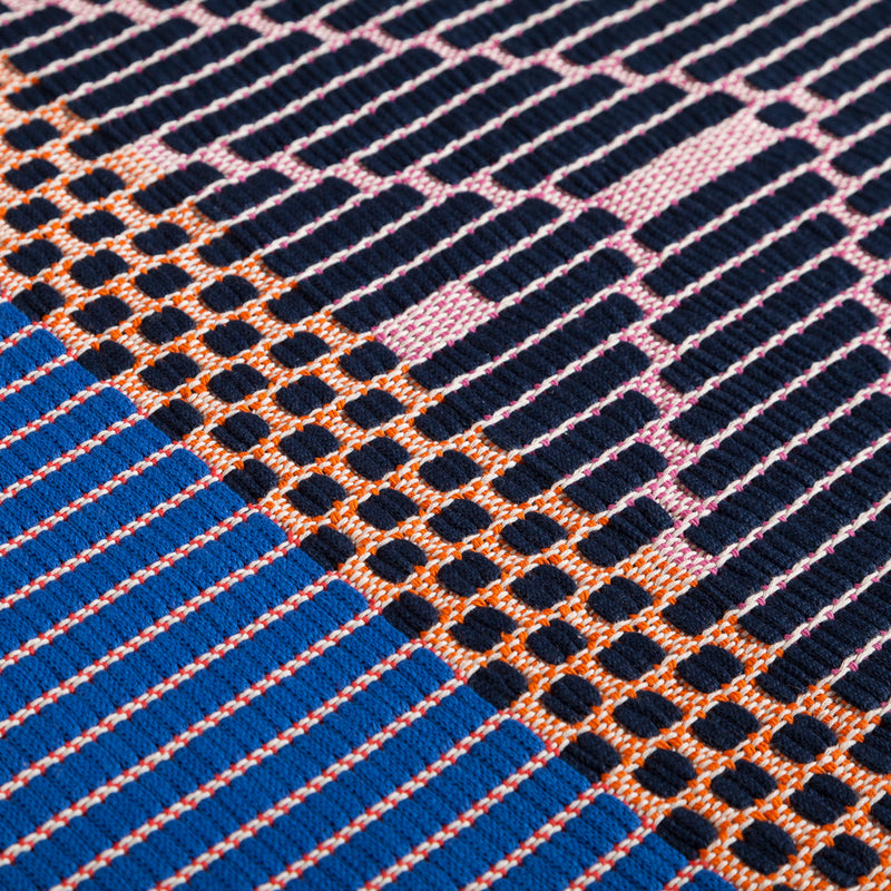 geometrikus mintájú élénk színű kék szőnyeg  ágy mellé